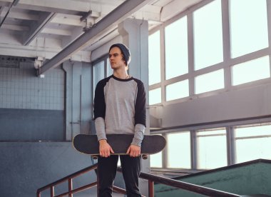 Holding onun yönetim kurulu ve uzağa bakarak skatepark kapalı, bir eziyet demiryolu yanında duran genç kaykaycı.