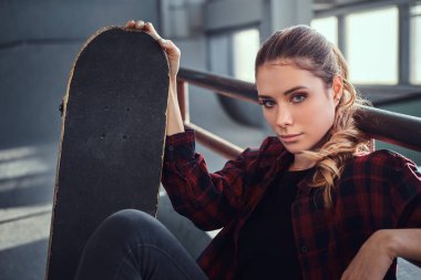 Çekici bir genç kız bir kaykay skatepark kapalı tutan bir kareli gömlek giyen portresi.