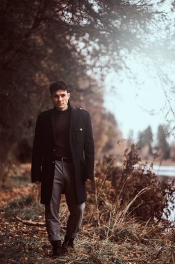 Yakışıklı bir genç adam sonbahar ormanda yürüyüş.