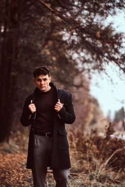 Sonbahar ormanda poz bir şık yakışıklı genç.