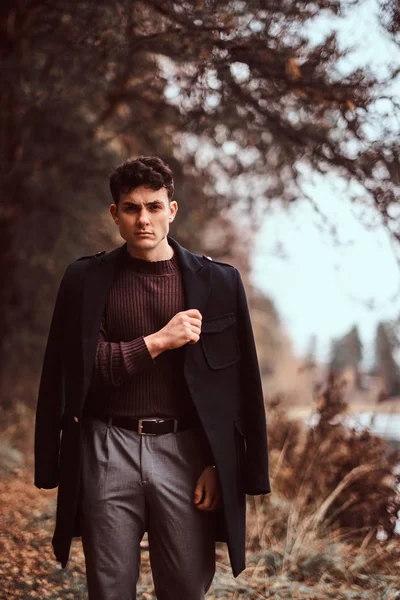 Joven con abrigo cubriéndose los hombros en el bosque otoñal . — Foto de Stock