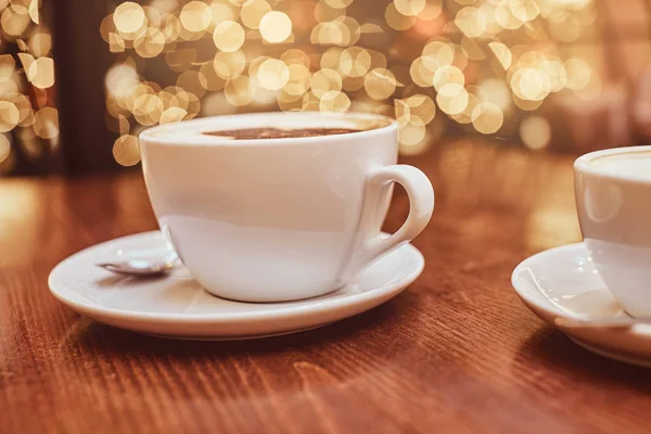 Горячий кофе с искусством в чашке на деревянном столе в кофейне, размытый фон с эффектом боке — стоковое фото