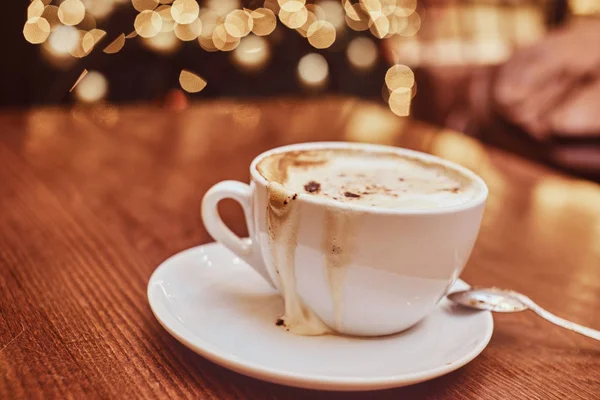 Tazza con caffè rovesciato sul tavolo di legno in una caffetteria, sfondo sfocato con effetto bokeh — Foto Stock