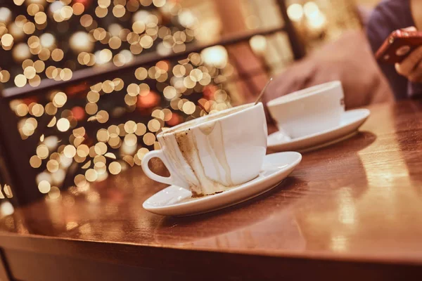 Δύο φλιτζάνια με καφέ έχουν χυθεί πάνω στο ξύλινο τραπέζι σε ένα κατάστημα καφέ, Θάμπωμα φόντου με bokeh αποτέλεσμα — Φωτογραφία Αρχείου