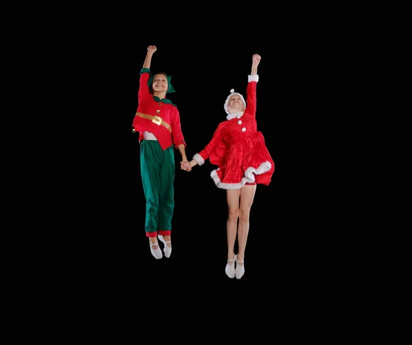 Christmas time, childhood, fairy tale. Cheerful kids - A young girl wearing a Santas costume and boy wearing elf costume flying together — Stock Photo, Image