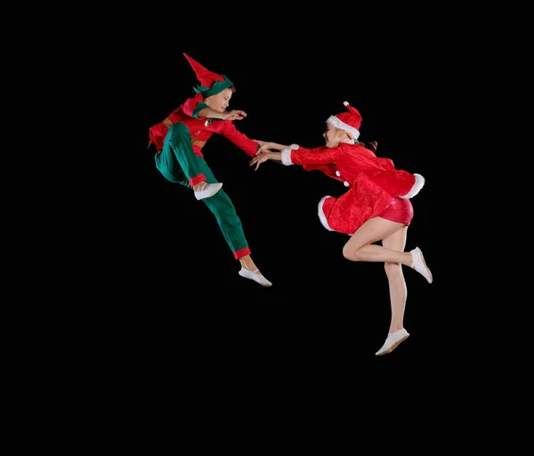 Christmas time, childhood, fairy tale. Cheerful kids - A young girl wearing a Santas costume and boy wearing elf costume flying together — Stock Photo, Image