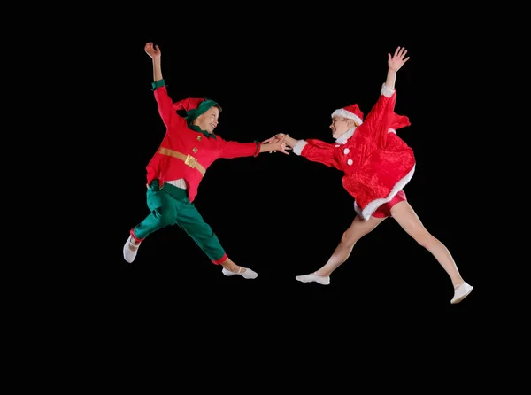 Natal, infância, conto de fadas. Uma jovem garota vestindo um traje de Pai Natal e menino vestindo traje de elfo voando juntos — Fotografia de Stock