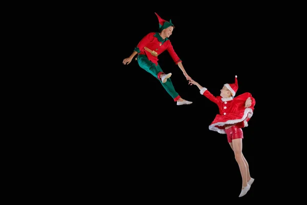 クリスマスの時、子供の頃、おとぎ話。サンタ衣装と少年のエルフ衣装が一緒に飛んでいる姿を着た少女 — ストック写真