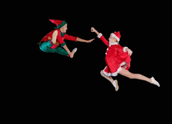 Natal, infância, conto de fadas. Uma jovem garota vestindo um traje de Pai Natal e menino vestindo traje de elfo voando juntos — Fotografia de Stock