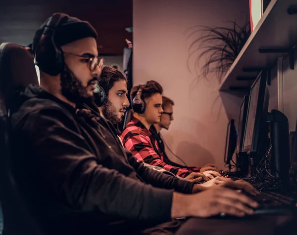 A young African American guy, enjoying spending time with his friends, playing in a multiplayer video game on a PC in a gaming club or internet cafe. — Stock Photo, Image