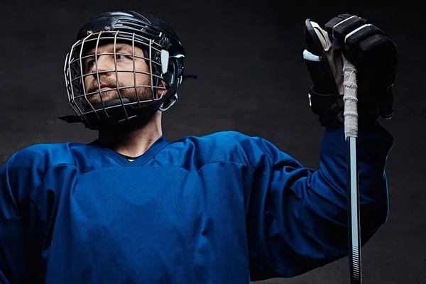 Retrato de um jogador barbudo de hóquei no gelo em um sportswear azul com vara de jogo. Estúdio . — Fotografia de Stock