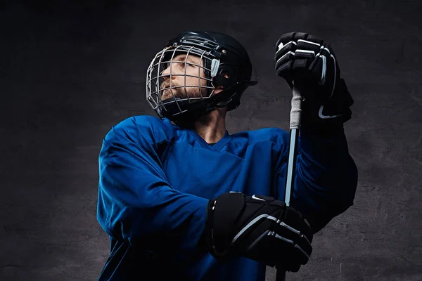 Retrato de um jogador barbudo de hóquei no gelo em um sportswear azul com vara de jogo. Estúdio . — Fotografia de Stock