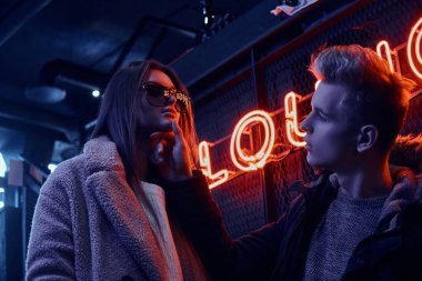 Tutkulu genç bir çift birbirine sahip endüstriyel iç yeraltı gece kulübünde bakarak portresi, dokunduğu yavaşça çenesi