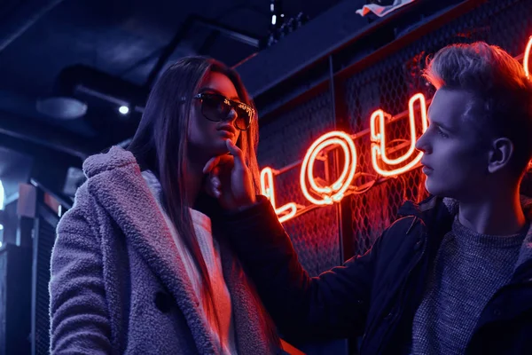 Retrato de una joven pareja apasionada mirándose en el club nocturno subterráneo con el interior industrial, toca suavemente su barbilla — Foto de Stock
