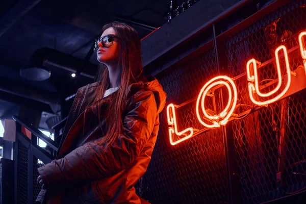 Mladé stylové dívka, která nosí bunda kabát a brýle stojí na schodech v klubu underground průmyslový interiér — Stock fotografie