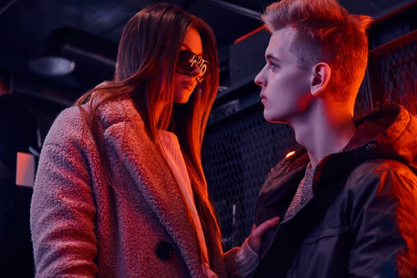 Una giovane coppia alla moda si guarda appassionatamente mentre si trova nel caffè con interni industriali, un cartello retroilluminato sullo sfondo — Foto Stock