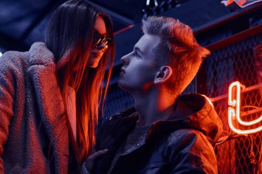 Ayakta kafeyi sanayi iç, arka plan arkadan aydınlatmalı tabela tutkulu genç çift trendy giyinmiş