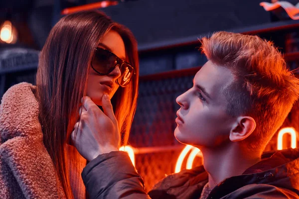 Gros plan portrait d'un jeune couple passionné se regardant dans la discothèque souterraine à l'intérieur industriel, il touche doucement son menton — Photo