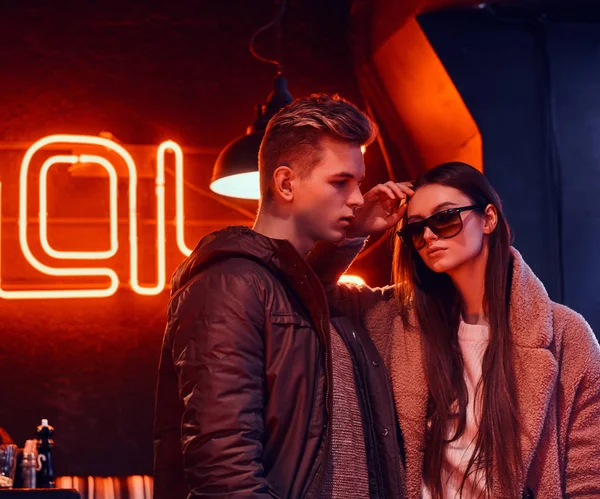 Atractiva pareja joven usando ropa elegante posando juntos en un café con interior industrial —  Fotos de Stock