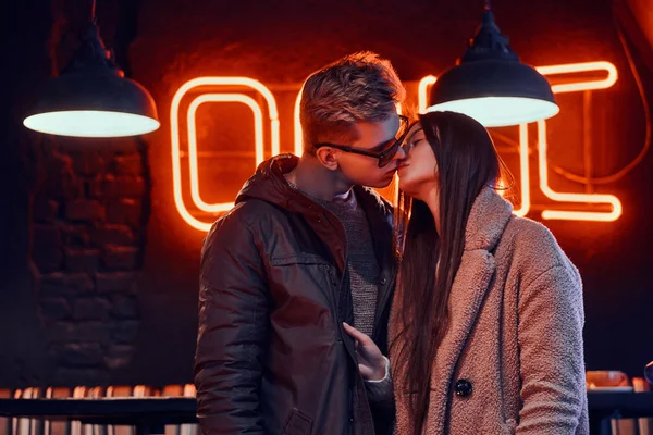 Пристрасна молода пара в стильному одязі цілується в кафе з промисловим інтер'єром — стокове фото
