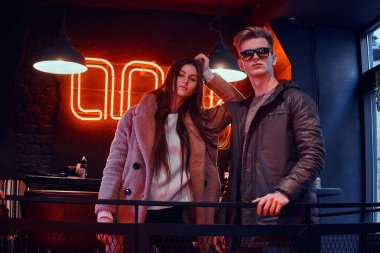 Bir kafede endüstriyel iç ile birlikte poz şık giysiler giyiyor çekici genç çift