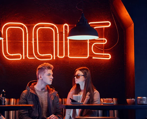 Модная молодая стильная пара сидит в кафе с промышленным интерьером — стоковое фото