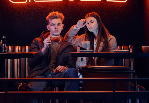 Trendy dressed young stylish couple sitting in a cafe with industrial interior — Stock Photo, Image