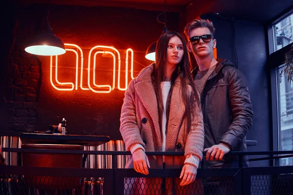 Çekici genç çift birlikte endüstriyel iç bir kafede ayakta şık giysiler giyiyor