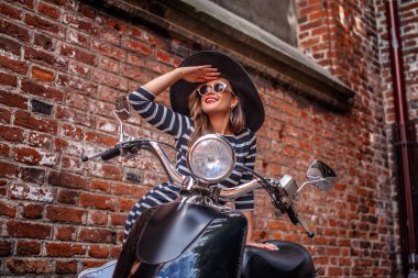 Neşeli kadın siyah klasik İtalyan motorla yaslanmış ve Avrupa'nın eski bir sokak uzakta arıyorum moda giyim.