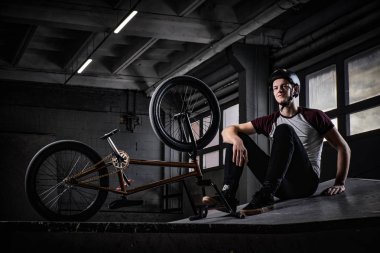 BMX sürücüsü hileler bir skatepark kapalı onun bisiklet ile pratik sonra rahatlatıcı