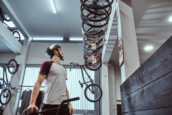 Jeune homme dans un casque de protection et de choisir un pneu de vélo pour son vélo dans la boutique — Photo