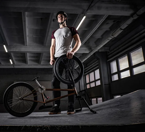 Портрет професійного гонщика BMX в захисному шоломі з велосипедом, що стоїть в скейтпарку в приміщенні — стокове фото