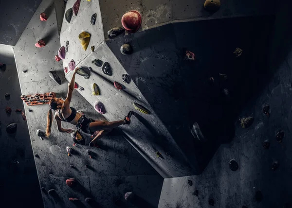 Sporty woman climbing artificial boulder indoors. — Stock Photo, Image