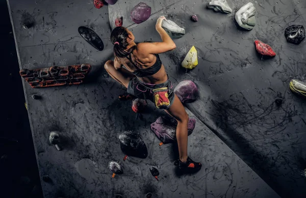 Sporty woman climbing artificial boulder indoors. — Stock Photo, Image