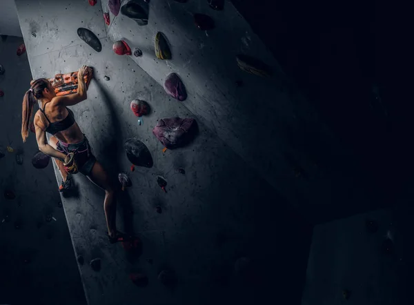 Sportliche Frau klettert künstlichen Boulder drinnen. — Stockfoto