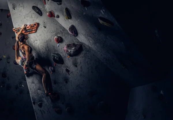 Sportliche Frau klettert künstlichen Boulder drinnen. — Stockfoto