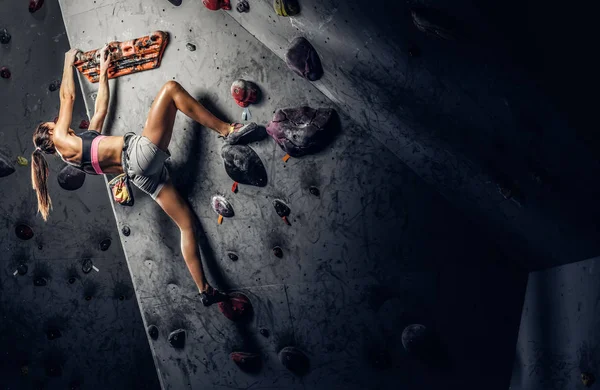 Sportovní žena lezení umělý kámen uvnitř. — Stock fotografie