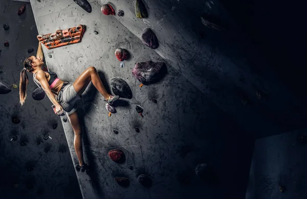 Sportowy kobieta wspinaczkowe sztuczne boulder pomieszczeniu. — Zdjęcie stockowe