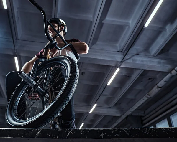 Adolescent BMX coureur assis sur son vélo dans un skatepark à l'intérieur — Photo