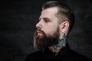 Profile portrait of an expressive bearded man with tattoos on his neck, isolated on a dark background. clipart
