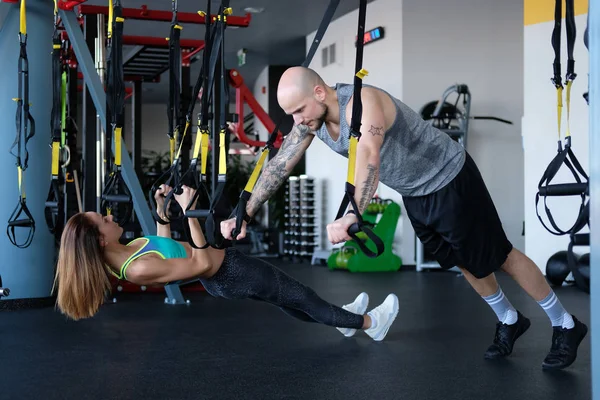 Séance d'entraînement en couple sportive dans la salle de gym, faire de l'exercice avec des boucles fonctionnelles . — Photo