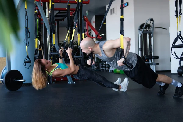 Sporty couple workout in the gym, doing exercise with functional loops. — Stock Photo, Image