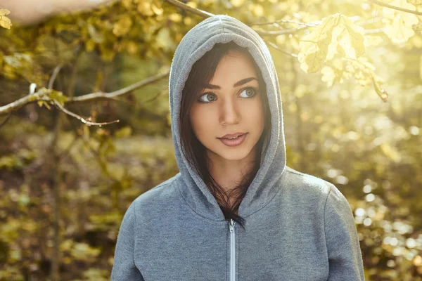 A charming girl wearing a gray hoodie in the autumn park — Stock Photo, Image