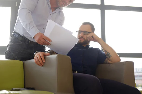 Coworkers examine important business documents at the office. — Stock Photo, Image