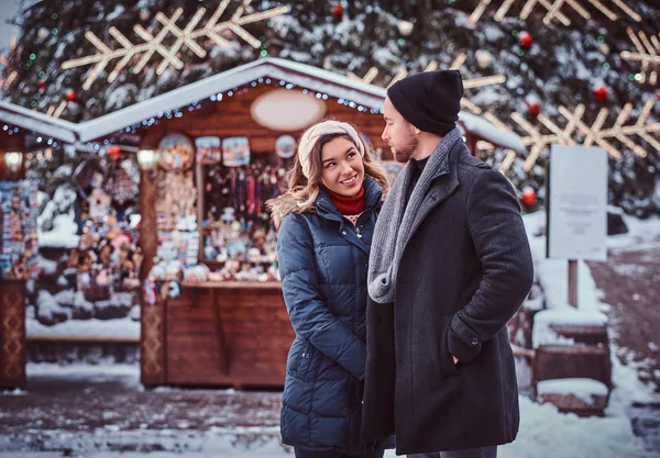 Feliz jovem casal vestindo roupas quentes em pé perto de uma árvore de Natal da cidade, gostando de passar o tempo juntos — Fotografia de Stock