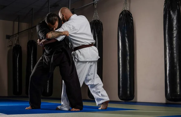 Dos luchadores de karate en kimono mostrando habilidad técnica en un club de lucha — Foto de Stock