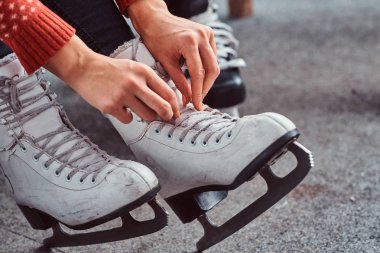 Genç bir çift bir paten için hazırlanıyor. Yakın çekim fotoğraf ellerinin buz hokeyi ayakkabı bağcığı bağlama soyunma odasında skates