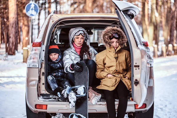 Güzel bir kadın ve onun oğlu bir arabanın bagajına oturan sıcak elbise giymiş — Stok fotoğraf