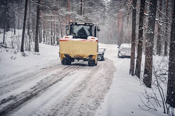 Bulldozer cleans snow-covered road through the forest