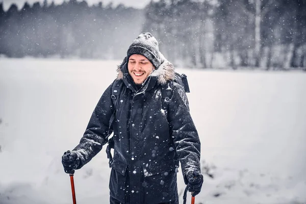 Ritratto di un escursionista con uno zaino che cammina attraverso un bosco invernale — Foto Stock